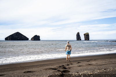 Rear view of woman walking at beach against sky