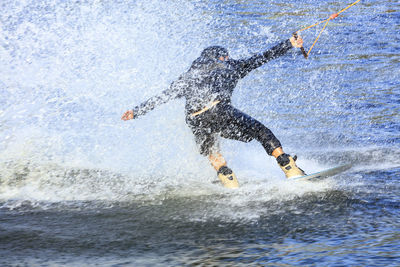 Full length of man splashing water while kiteboarding in sea