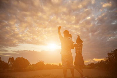 Friends standing against sky during sunset