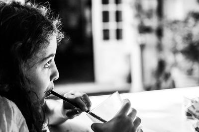 Close-up side view of girl drinking from straw