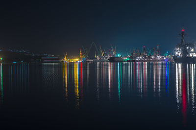 Illuminated pier over sea against sky at night