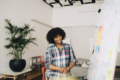 Portrait of smiling woman standing against wall