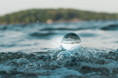 Close-up of crystal ball by bubbles at beach