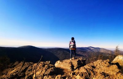 Rear view of people standing on mountain against blue sky