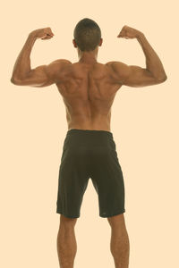 Rear view of shirtless man standing against white background