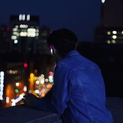 Man standing on building terrace in city at night