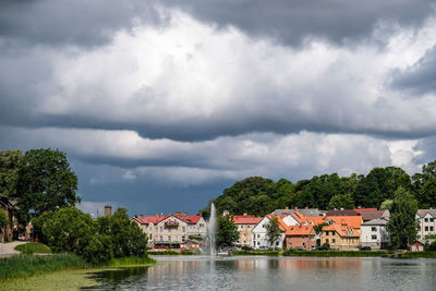 Buildings by lake against sky