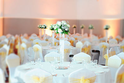 Place setting on tables amidst chairs arranged during wedding ceremony