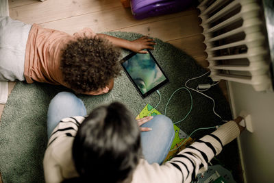 Directly above shot of mother and son charging digital tablet at home