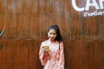 Portrait of a smiling young woman standing on wood