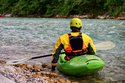 Rear view of man with umbrella on river