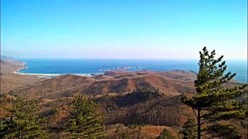 Scenic view of sea and mountain against blue sky