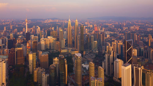 Aerial view of illuminated cityscape against sky during sunset