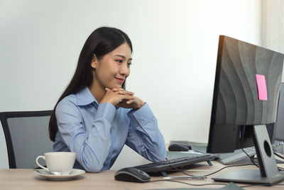 Young woman using mobile phone while sitting on table