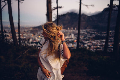 Rear view of woman with arms raised against sky during sunset