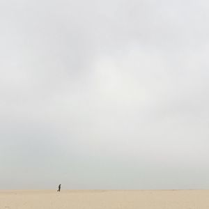 Man walking in desert against clear sky