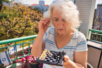 Elderly gray-haired woman learning to play chess