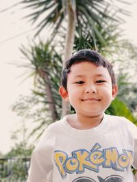 Portrait of boy standing against tree