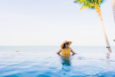 Young woman in swimming pool against sky