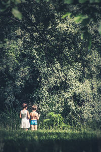 Rear view of siblings standing in forest