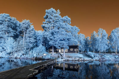 Frozen lake by trees against clear sky during winter