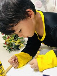 Rear view of boy holding yellow flowering plant