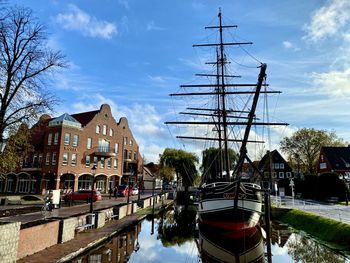 Sailboats in canal amidst buildings against sky