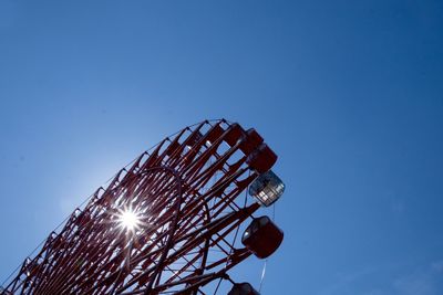 Low angle view of ferris wheel against blue sky