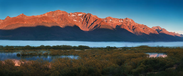 Scenic view of lake by mountains against sky