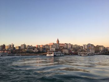 Sea by buildings against clear sky