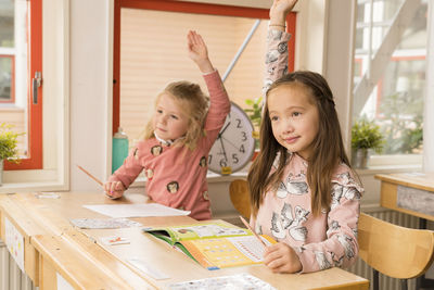 Girls in classroom raising hands