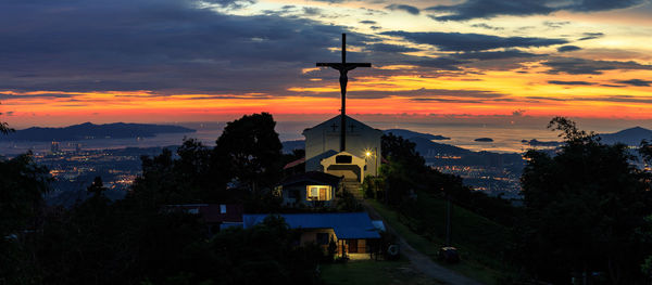 Crucifix on church against sky during sunset