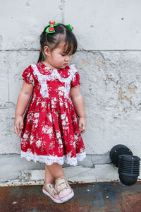 Cute girl wearing vintage red dress standing against the wall