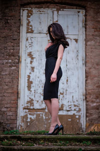 Full length of woman standing against wall
