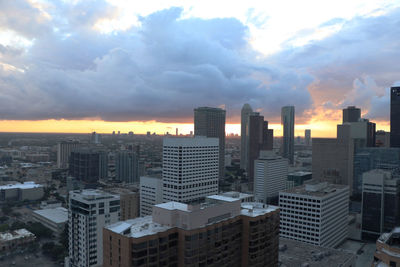 Modern buildings in city against sky during sunset