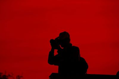 Silhouette man and woman standing against red orange sky