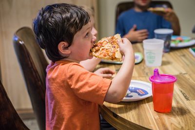 Girl eating food while sitting on table