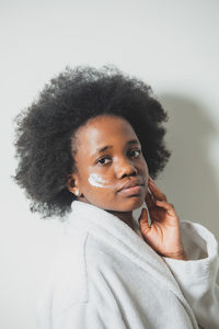 Portrait of young woman with curly hair against white background