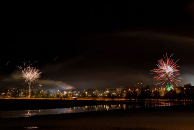 Firework display over river against sky at night
