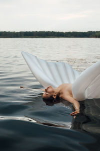 Midsection of woman on lake against sky