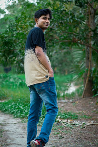 Young man looking away while standing on land