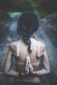 Rear view of shirtless woman standing with hands clasped on road