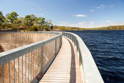 Wooden bridge over water against sky