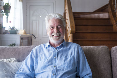 Portrait of senior man sitting on sofa at home