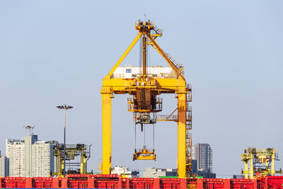 Cranes at commercial dock against clear sky