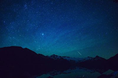 Scenic view of snowcapped mountains against star field at night