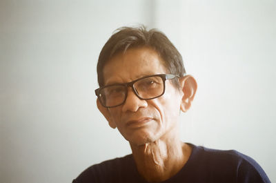 Portrait of man wearing eyeglasses against white background