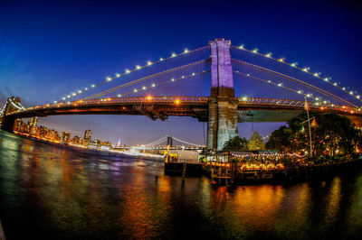 Illuminated suspension bridge over river at night