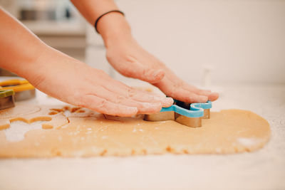 Cropped hand of woman pushing mold on cookie dough