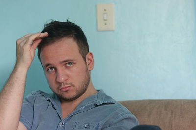 Portrait of young man sitting against wall